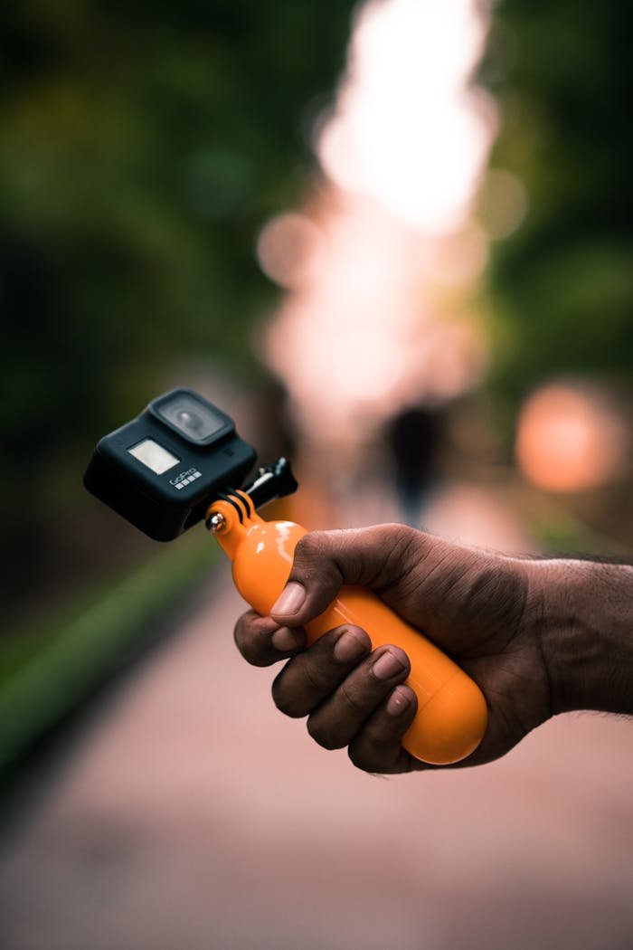 Close-up of a person holding an action camera with a blurred background.